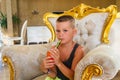 Boy sits in a chair and drinks fruit juice at the hotel