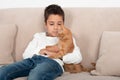 The boy sits on the couch and plays with the little red kitten in the room Royalty Free Stock Photo