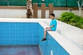 A boy sits by an empty pool. Concept summer 2020. No tourism