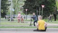 A boy sits on the grass beside a tree in the park