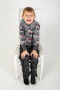 The boy sits and grimaces on a chair on a white background Royalty Free Stock Photo
