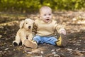 Boy sits on the ground the autumn leaves lie on the ground. Royalty Free Stock Photo