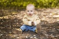 Boy sits on the ground the autumn leaves lie on the ground. Royalty Free Stock Photo