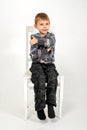 The boy sits with his arms around himself on a chair on a white background Royalty Free Stock Photo