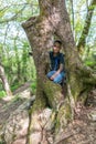 The boy sits in the hollow of a large old tree Royalty Free Stock Photo