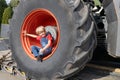 boy sits in a huge tractor wheel, looks into the frame, smiles Royalty Free Stock Photo