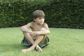 The boy sits on a lawn