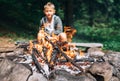 Boy sits near campfire. Summer camping time