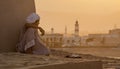 Boy sits next to a wall watching the sunset