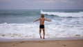 Boy sits on the ocean shore with his arms open towards wind and waves. Storm in summer, courage