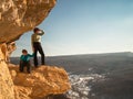 The boy sits on a rock near the mother