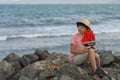 The boy sits on a stony seashore