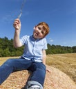 boy sits on top of a golden straw stack