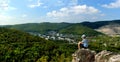 The boy sits on the top of the mountain and enjoys a panoramic view of the verdant valley and the city of Zhigulevsk.