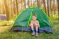 The boy sits in the tourist tent in the green forest Royalty Free Stock Photo