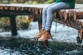 Boy sits on the wooden bridge over the river. Close up legs in b Royalty Free Stock Photo