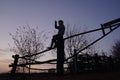 The boy sits on a wooden fence against the background of sunset sky and points finger into the distance. Rural motifs Royalty Free Stock Photo