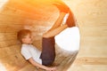 Boy sits in a wooden tunnel with legs up. Eco-friendly natural playground. Soft light