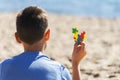 Boy sitting on the beach, looking to the sea ocean and holding colorful autism awareness heart