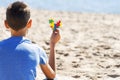 Boy sitting on the beach, looking to the sea ocean and holding colorful autism awareness heart