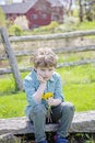 Boy sitting on bench with bouquet of fresh picked flowers Royalty Free Stock Photo