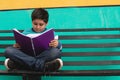 Boy sitting on a bench reading a book Royalty Free Stock Photo