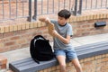 Boy sitting on bench taking book from backpack at school Royalty Free Stock Photo
