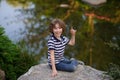 Boy sitting on a boulder near the water