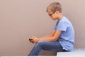 Boy sitting with cell phone and play online games outdoors