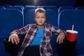 Boy sitting in cinema theatre, watching movie attentively.