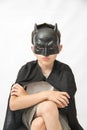 Boy sitting down and wearing a Batman mask