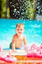 Boy sitting on the edge of the pool and smiling next to the pink flamingo float Royalty Free Stock Photo