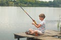 Boy sitting and fishing from a dock