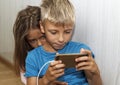 boy is sitting on the floor and playing mobile games on her phone. girl sits next to him and worries about the process of playing Royalty Free Stock Photo