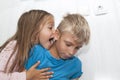 boy is sitting on floor and playing Mobile games on his phone. girl sits next to him and shouts in his ear while playing friend Royalty Free Stock Photo