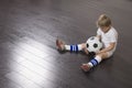 Boy Sitting On Floor With Soccer Ball