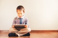 Boy sitting on the floor using a tablet absorbed in it Royalty Free Stock Photo