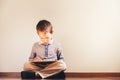 Boy sitting on the floor using a tablet absorbed in it Royalty Free Stock Photo