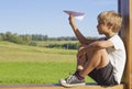 Boy sitting and flying a paper in summer day