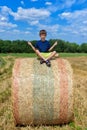 The boy is sitting on golden hay bales on the field Royalty Free Stock Photo