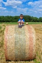 The boy is sitting on golden hay bales on the field Royalty Free Stock Photo