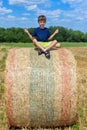 The boy is sitting on golden hay bales on the field Royalty Free Stock Photo