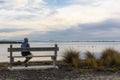 Man sitting on his back on a wooden bench watching the ducks in the water Royalty Free Stock Photo