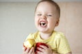 The boy is sitting on the kitchen table eating an Apple and laughing very hard Royalty Free Stock Photo