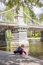 Boy sitting by lake in Boston public garden by bridge Royalty Free Stock Photo