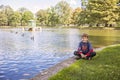 Boy sitting by lake in Boston public garden with geese