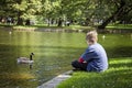 Boy sitting by lake in Boston public garden with a goose Royalty Free Stock Photo