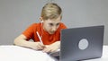 A boy sitting at a laptop at an online conference undergo training