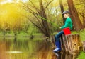 Boy sitting, looking at water and fishing on pond