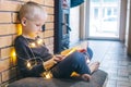 Christmas background. The boy is sitting near the fireplace with a book. Child with yellow lights. Waiting for the new year. Royalty Free Stock Photo